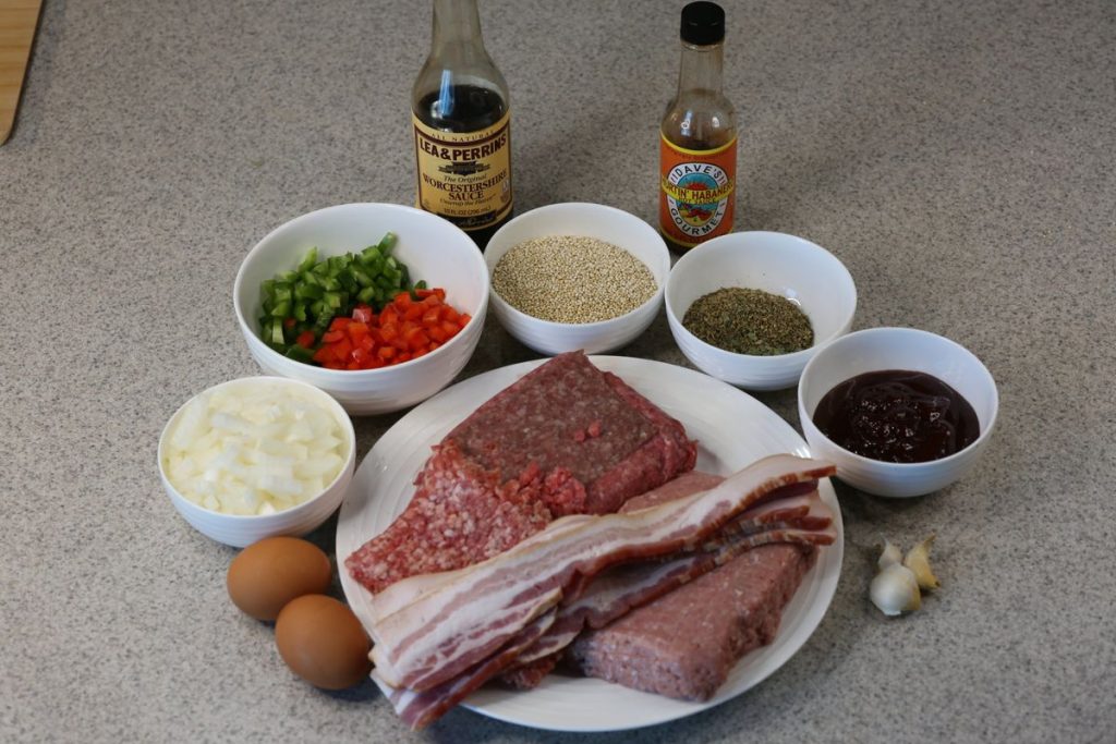 Ingredients for gluten-free four-meat meatloaf: ground beef, ground turkey, Italian sausage, bacon, diced peppers and onion, dry quinoa, Italian seasoning, eggs, garlic, barbecue sauce, Worcestershire and hot sauce