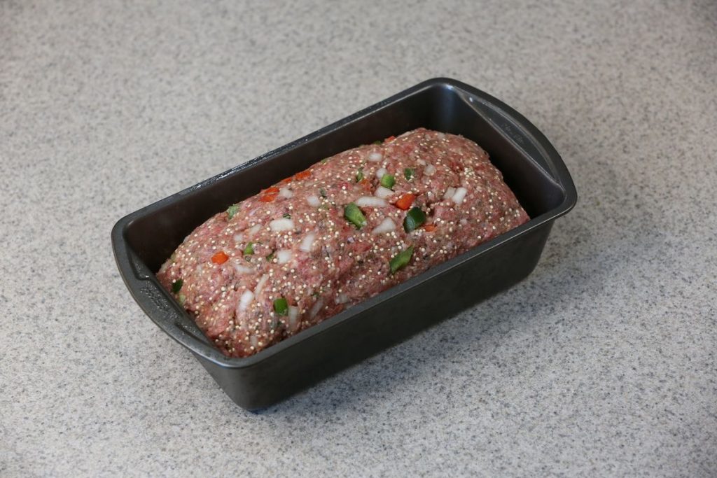 Meatloaf mixture shaped with a mounded top in a 9x5-inch loaf pan, with room around the edges