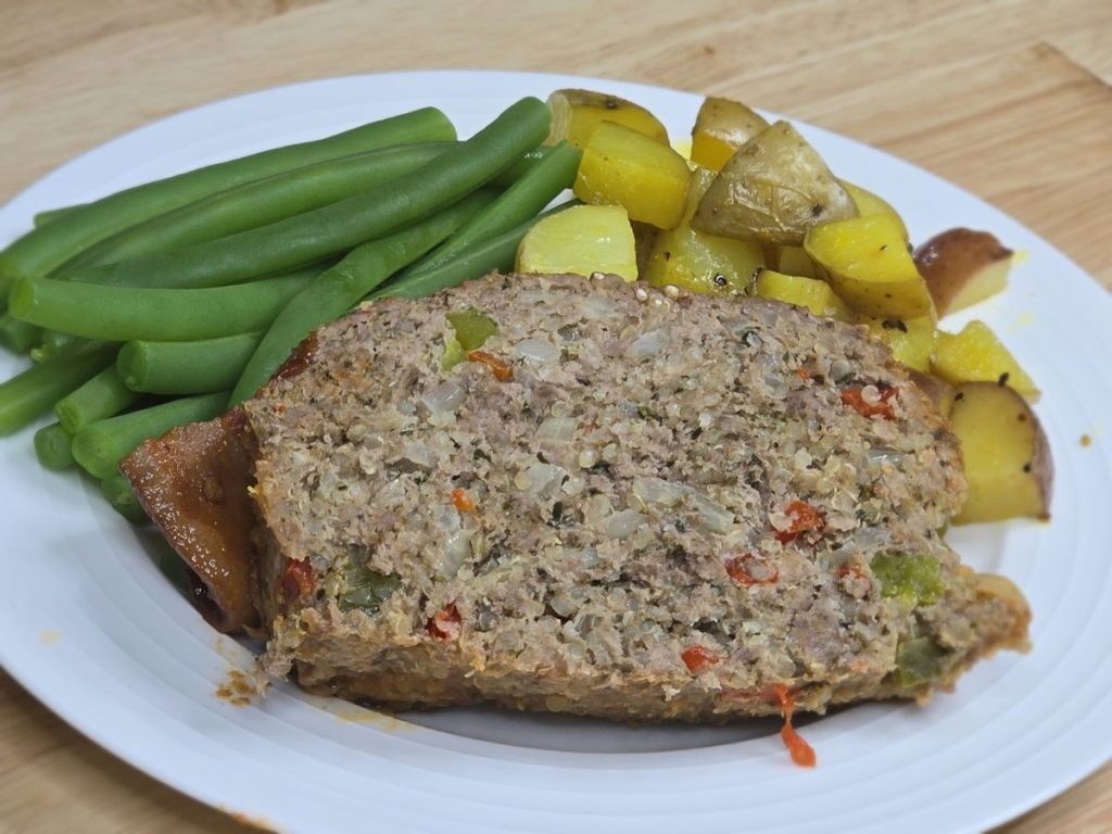 Slice of gluten-free quinoa meatloaf served with green beans and roasted potatoes